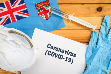 Coronavirus in Fiji. Flag of Fiji, vaccine, face mask for virus, glove and paper sheet with words Coronavirus COVID-19