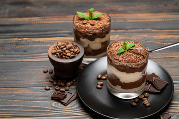 Classic tiramisu dessert in a glass cup on wooden background