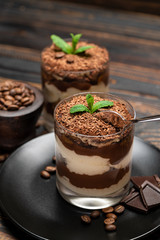 Classic tiramisu dessert in a glass cup on wooden background