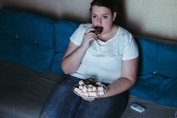Emotional eating, mental disorder, depression, loneliness, stress. Lonely woman eating sweets and watching tv late in the night. Nerve food