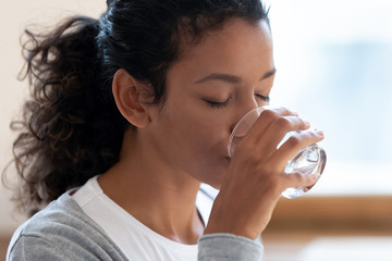 Thirsty african American woman drinking mineral water