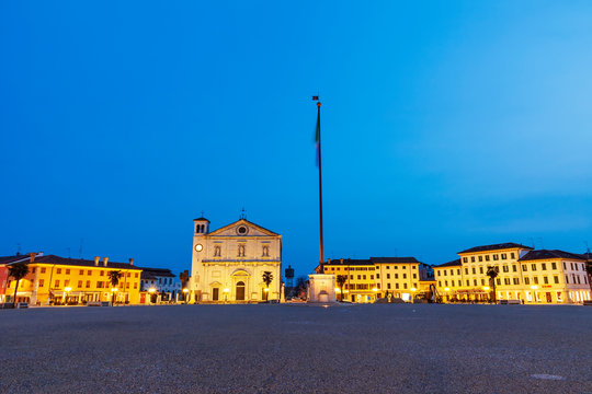 Piazza Grande a Palmanova fotografia notturna. Visibile il duomo con il serbatoio idrico e il pennone con bandiera italiana.