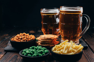 Beer and appetizing snacks. table with two mugs of craft lager and salty traditional appetizers. Finger food. Oktoberfest food, pub concept