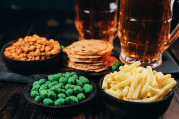 Beer and salty snacks. table with two mugs of craft lager and crunchy appetizers. Oktoberfest food, pub concept