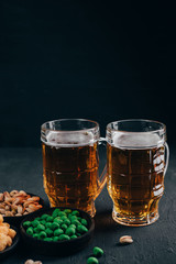 Beer and appetizing snacks. table with two mugs of craft lager and salty traditional appetizers. Finger food. Oktoberfest food, pub concept