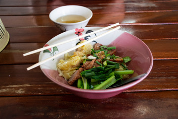 Dried noodles, dumplings, pork, Chinese cabbage in a bowl.