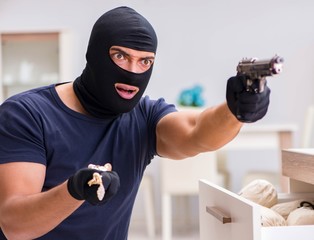 Robber wearing balaclava stealing valuable things