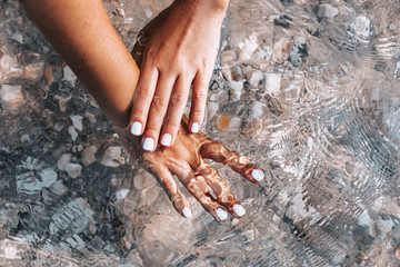 close up of beautiful woman hands with manicure under water outdoors