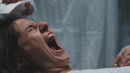 woman in labor in maternity ward gives birth to child pushing haard and scream and shout, portrait of young Caucasian pregnant mother waiting for baby and feeling severe pain - Powered by Adobe