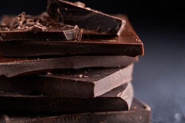 Piece of dark chocolate and chocolate chips on a dark background Close up