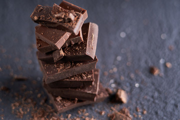 Piece of dark chocolate and chocolate chips on a dark background