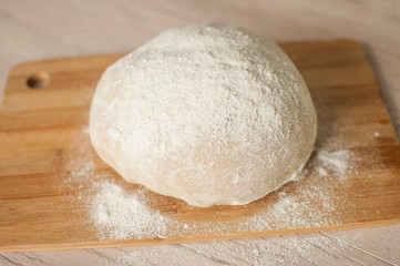Fototapeta na wymiar Round piece of dough on a wooden cutting board