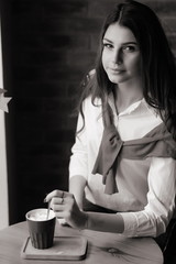 Girl at a table by the window in a cafe with a cup of coffee