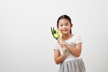 little girl holding yellow tulips on white