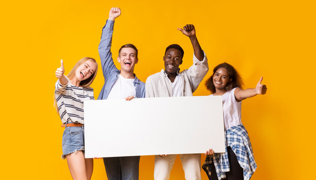 Portrait of excited group of teenagers holding empty advertising board