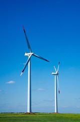 Wind turbines on green field blue sky clouds green energy concept renewable energy generator
