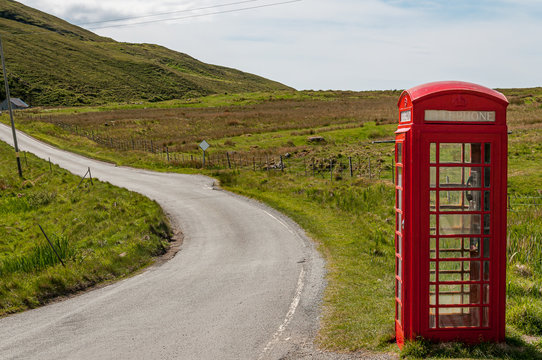 Isolated telephone booth near a road in the Scottish Highlands. Concept: communications in isolated places, English symbol, Scottish landscape