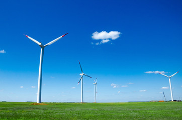 Fototapeta premium Wind turbines on green field blue sky clouds green energy concept renewable energy generator