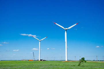 Fototapeta premium Wind turbines on green field blue sky clouds green energy concept renewable energy generator
