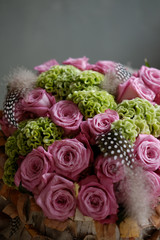 Beautiful spring bouquet close-up with pink roses and green carnations, decorated with feathers and birch bark. 