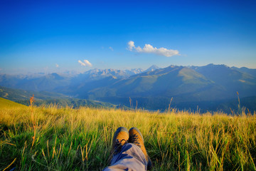   Photo of the legs. Mountain boots. Mountain panorama. A place for relaxation. Holidays in the mountains. Good light.
