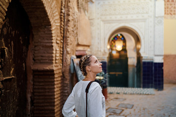 Fototapeta na wymiar Travel and active lifestyle concept. Young traveller woman walking in ancient moroccan town.