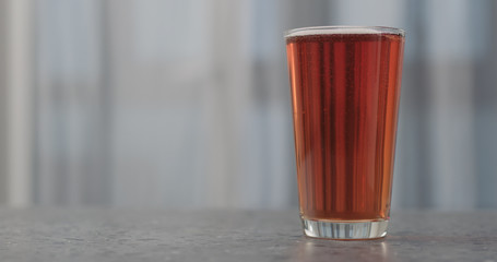 orange fizzy drink in pint glass on concrete countertop with copy space