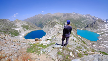 Girl in the mountains between two lakes. Beautiful mountain landscape. Blue lake in the mountains. Daylight. Tourist girl on the pass.
