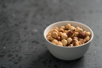 roasted hazelnuts in white bowl on concrete background