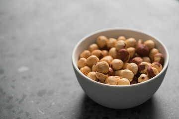 roasted hazelnuts in white bowl on concrete background