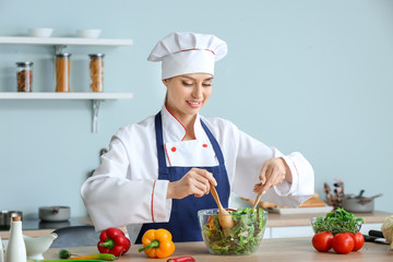 Female chef making fresh salad in kitchen