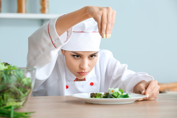 Female chef making fresh salad in kitchen