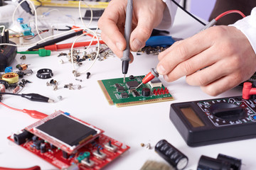 Faceless technician repairing smartphone's motherboard in lab, radioman soldering spare part of computer. Concept of computer hardware, mobile phone, electronic, repairing, upgrade and technology.