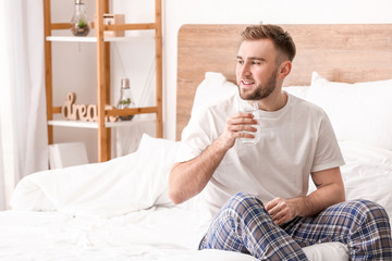 Morning of young man drinking water in bedroom