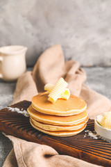 Tasty pancakes with butter on board