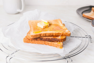 Tasty toasted bread with honey and butter on cooling rack