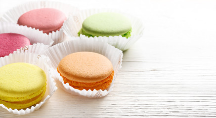 Colorful macarons cakes in paper baskets on white wooden background. Copy space