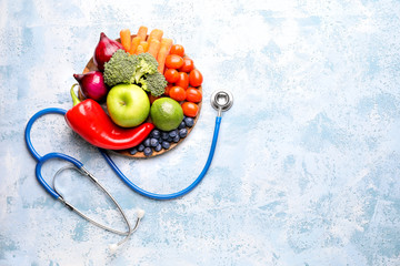 Plate with healthy products and stethoscope on color background