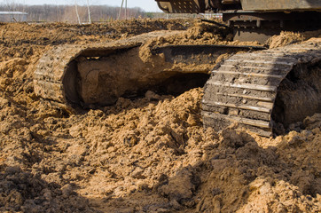 the tracks of a bulldozer, covered in mud, close-up