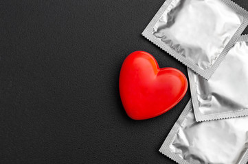Red heart with condoms on black background. Safe sex concept.