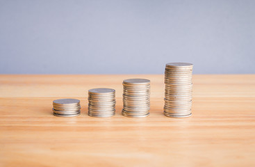 stack of coins on wooden desk with grey background