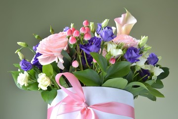 Spring bouquet in the box with pink ribbon. Floral composition with ranunculus, roses and alstroemerias flowers on neutral background 