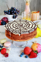 Halloween chocolate spider web cake and various fruits around.