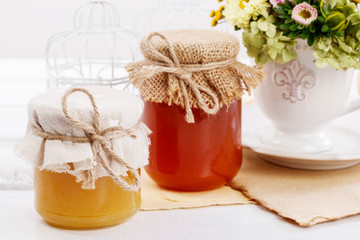 Jars with honey and bouquet of wild flowers on the table.