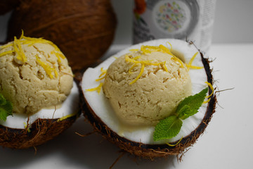 Food photo close-up coconut ice cream for raw foodists in coconut halves with lemon zest.