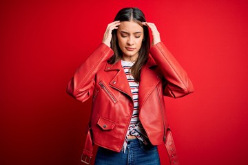 Young beautiful brunette woman wearing casual jacket standing over red background with hand on head for pain in head because stress. Suffering migraine.