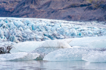 Vatnajoekull glacier in Iceland ice floes in glacier lake in front of blue and ash colored glacier