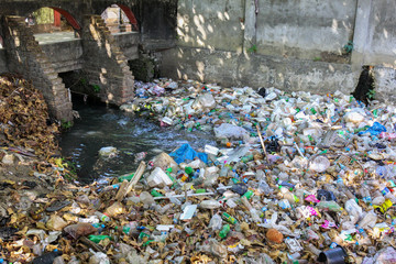 Yangon, Myanmar - January 01.2017: Plastic bottles and takeaway food containers carelessly thrown away into a sewage water system in an asian market place