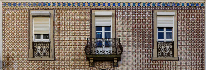 Obraz premium Element of the facade of the house. Old building with a brown wall is decorated with Azulejo, Lisbon, Portugal.