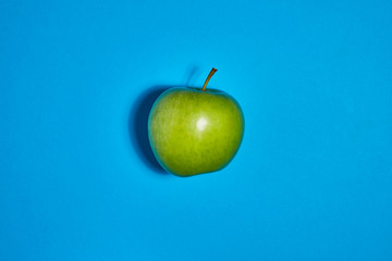 Green apple on blue background. Flat lay, top view, copy space . Food dietary concept.